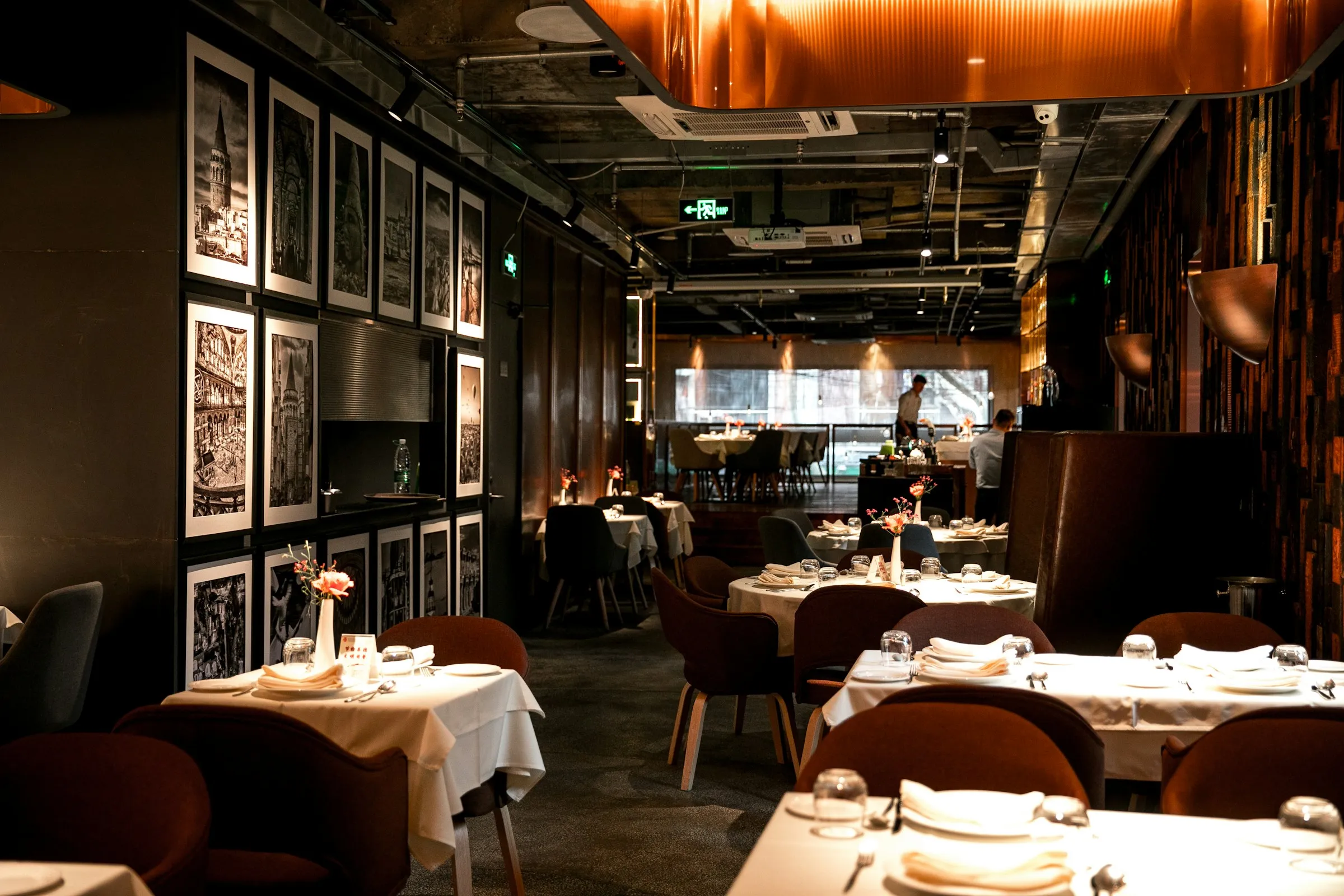 Hochwertiges Restaurant mit warmem Licht, weißen Tischdecken und Kunst an der Wand