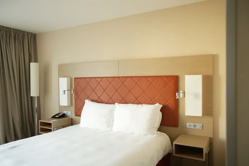 Hotelzimmer mit Kopfteil in Lederoptik und Wandpaneelen in heller Holzoptik