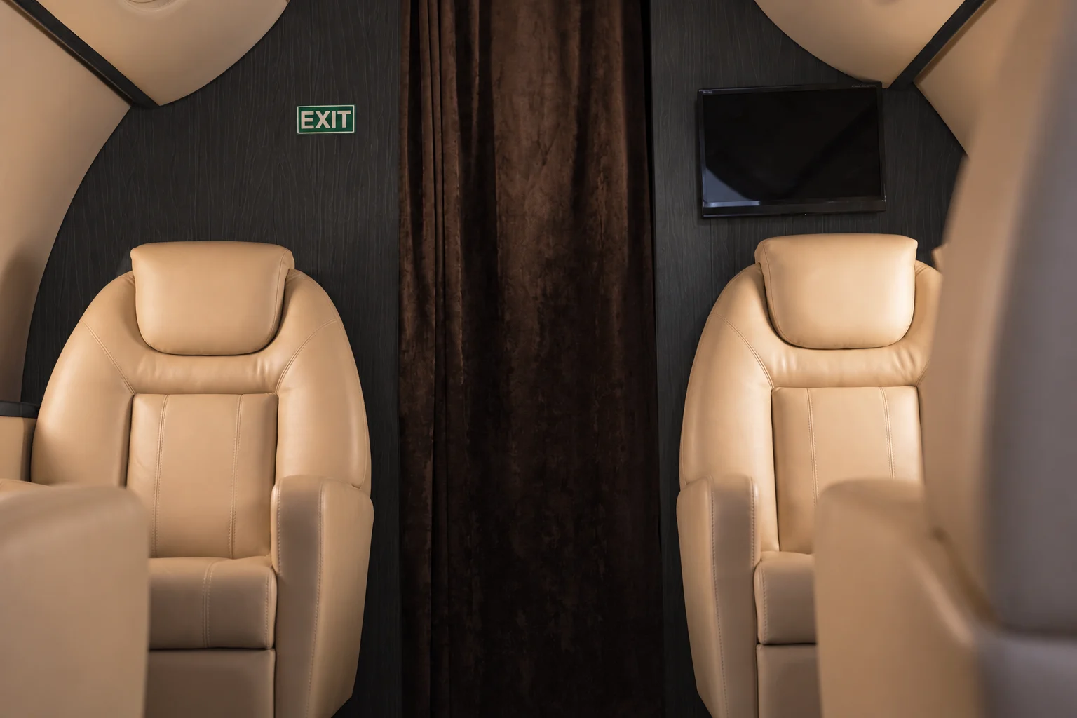Kabine eines Privatjets mit Ledersitzen und Paneelen in dunkler Holzoptik